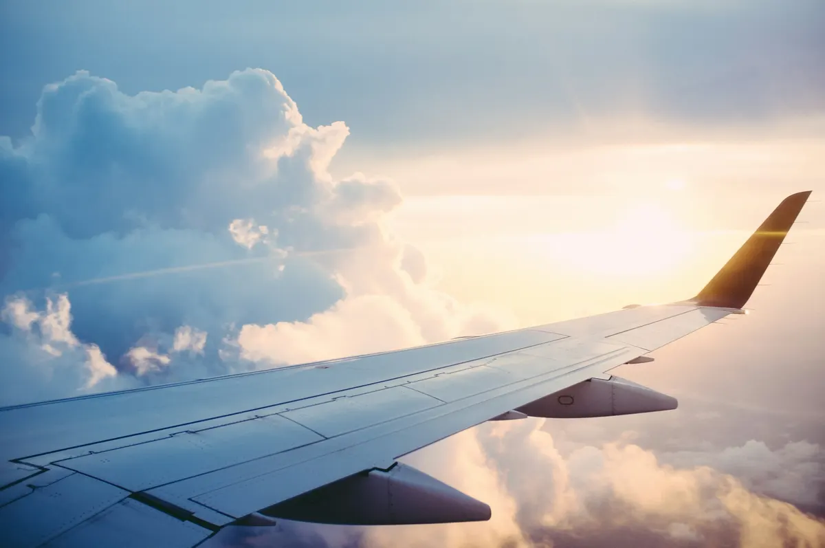 Ala de un avión sobre las nubes al atardecer